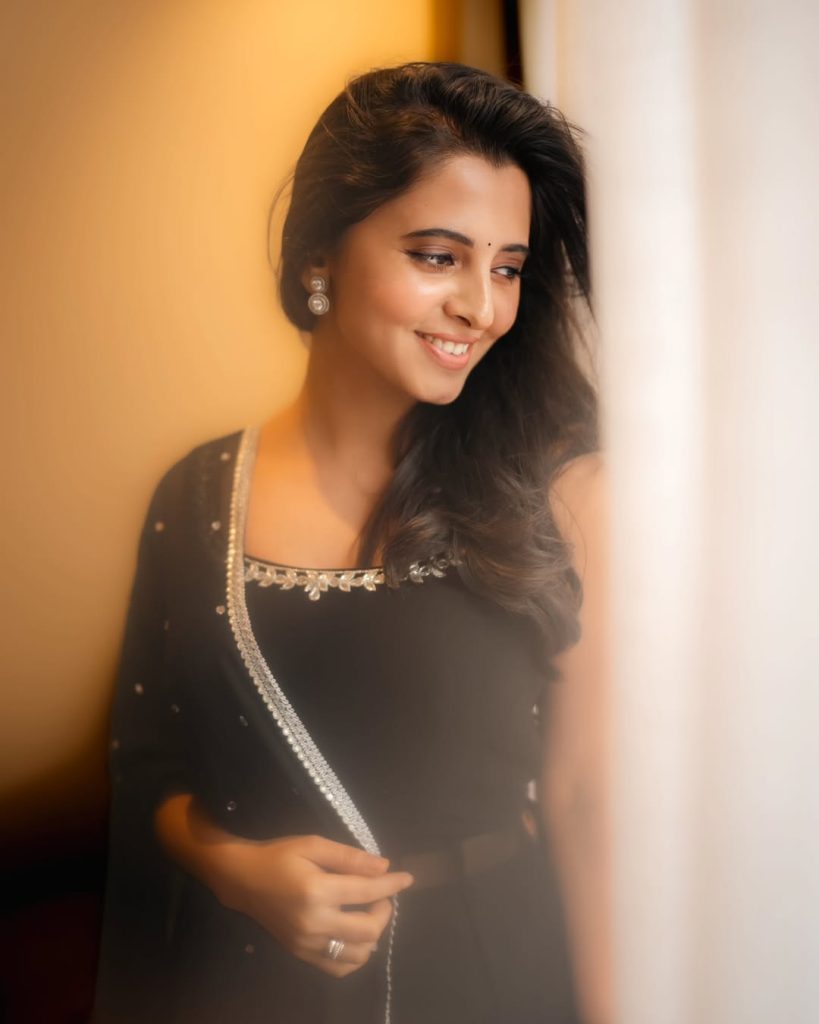 Preethi Asrani posing elegantly in fitted black dress ensemble