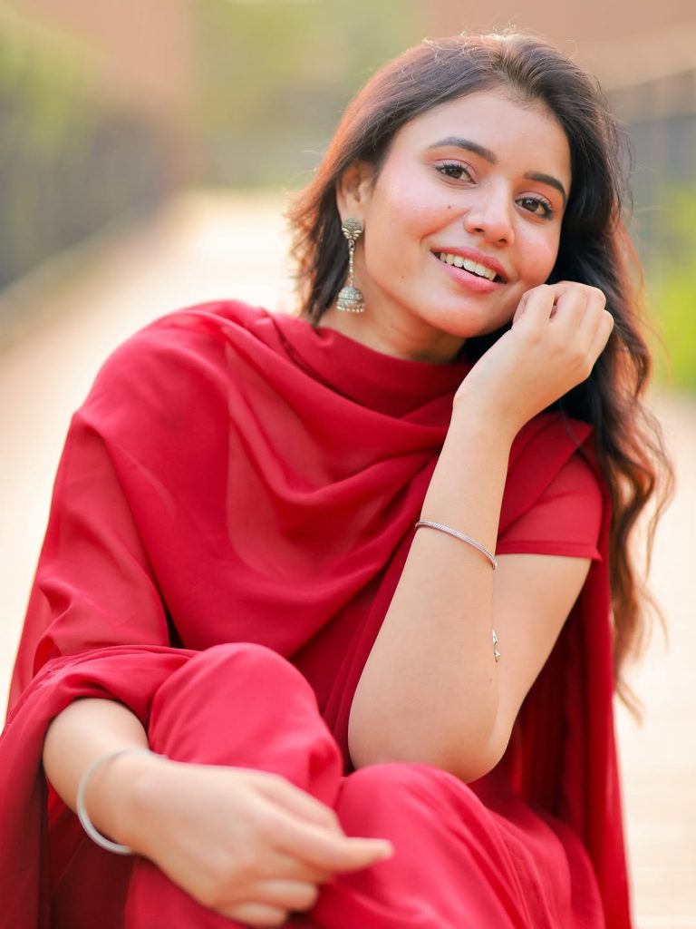Beautiful red chudidhar fabric drapes gracefully on Arul Jyothi's figure