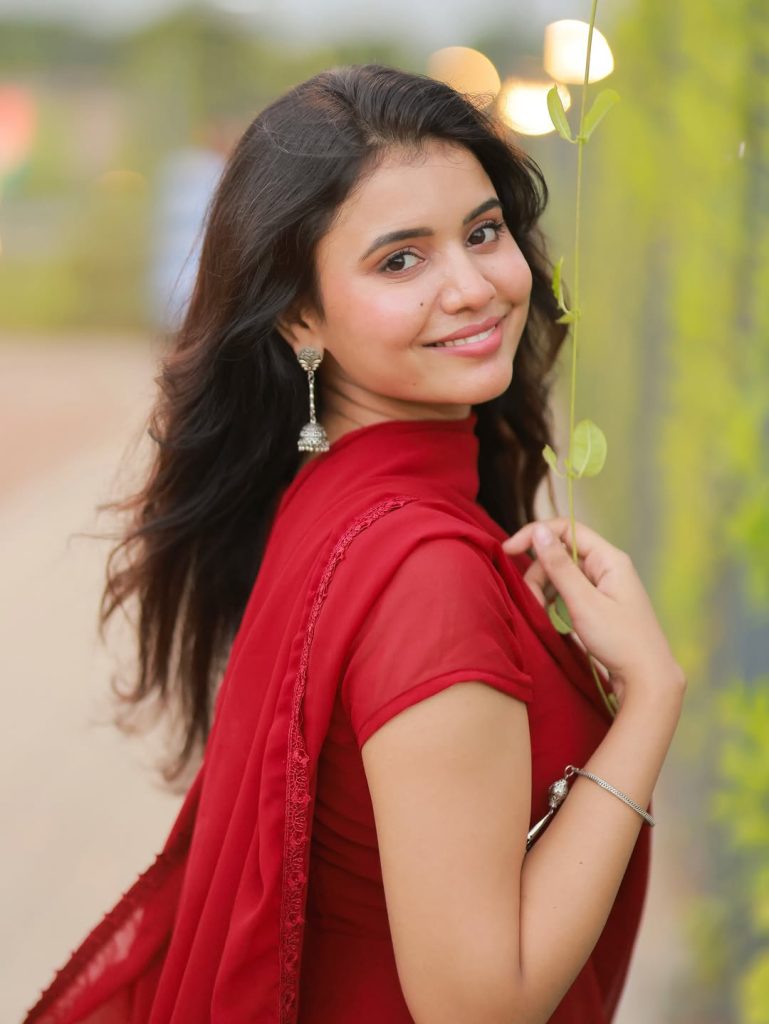 Beautiful red chudidhar fabric drapes gracefully on Arul Jyothi's figure
