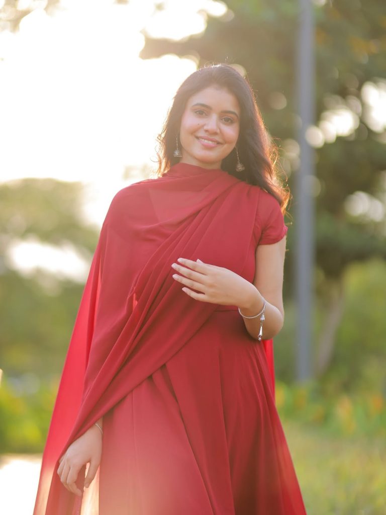 Beautiful red chudidhar fabric drapes gracefully on Arul Jyothi's figure