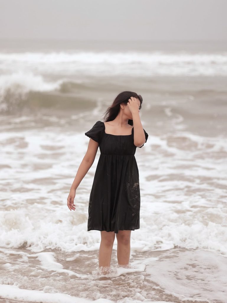 Ocean waves provide natural backdrop for Arul Jyothi's black dress beach styling
