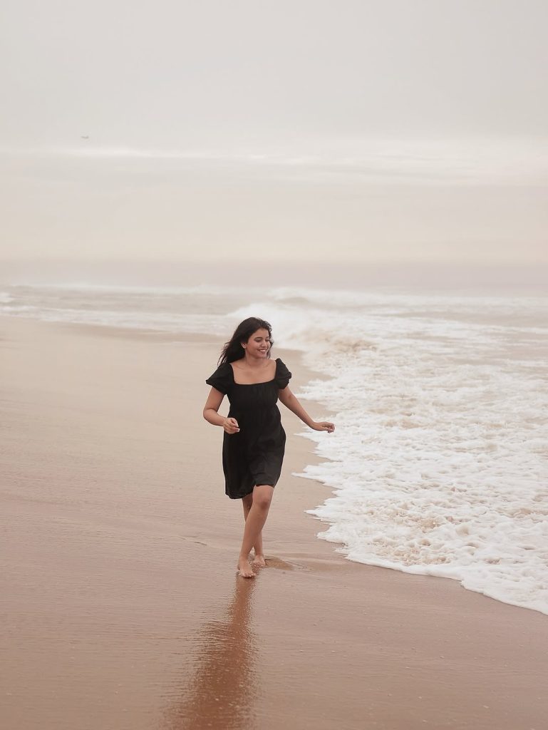 Ocean waves provide natural backdrop for Arul Jyothi's black dress beach styling