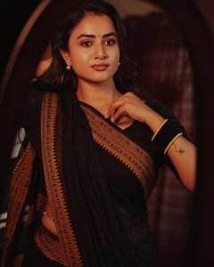 Outdoor gallery setting showcases Janani Ashok Kumar's black saree with yellow border