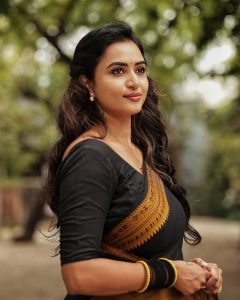 Outdoor gallery setting showcases Janani Ashok Kumar's black saree with yellow border