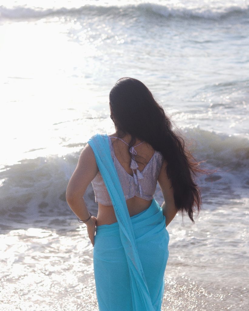 photoshoot captures Kanduri Sudha in traditional blue drape against ocean