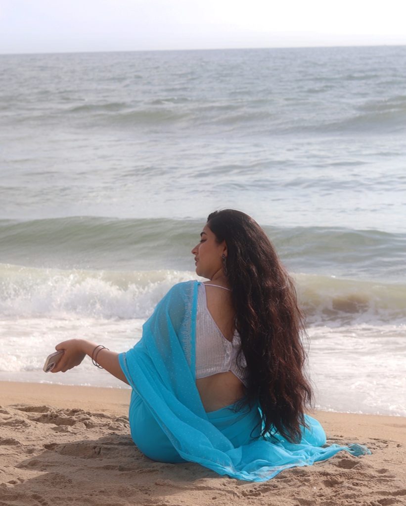 photoshoot captures Kanduri Sudha in traditional blue drape against ocean