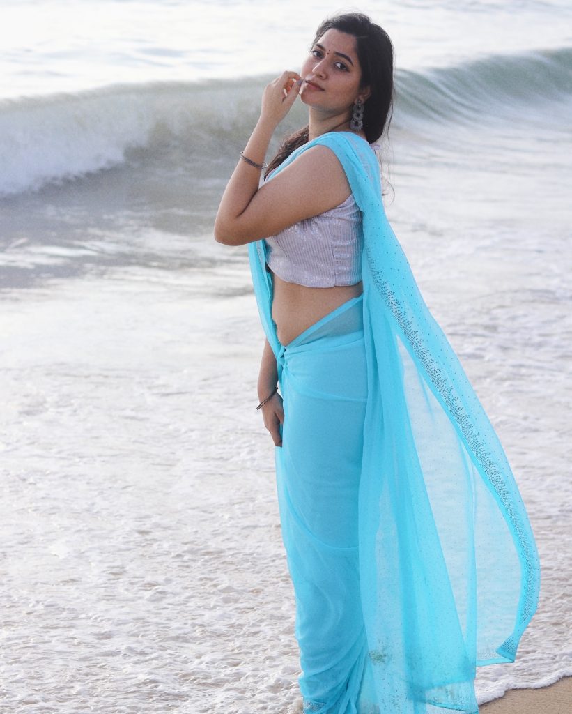 Beach waves backdrop frames Kanduri Sudha's flowing blue saree beautifully