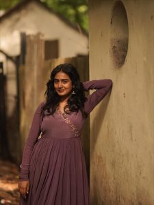 Casual outdoor setting showcases Yoga Lakshmi's elegant purple pleated gown