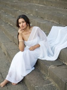 Serene portrait of Aarushi Baruah in white saree natural lake backdrop