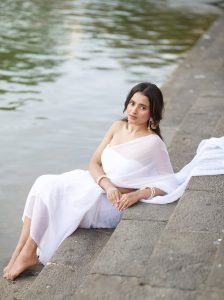 Serene portrait of Aarushi Baruah in white saree natural lake backdrop