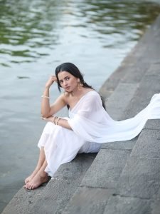 Serene portrait of Aarushi Baruah in white saree natural lake backdrop