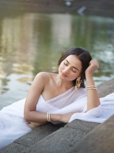 Aarushi Baruah white chiffon saree flowing by calm lakeside
