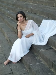 Aarushi Baruah white chiffon saree flowing by calm lakeside