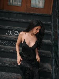 Disha Patani posing on outdoor steps in black slip dress under sunlight