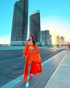 Eshanya Maheshwari twirling in orange dress on sandy beach