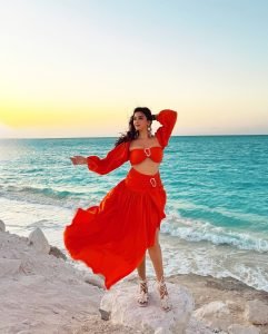 Eshanya Maheshwari twirling in orange dress on sandy beach