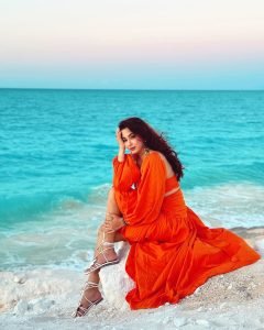 Eshanya Maheshwari twirling in orange dress on sandy beach