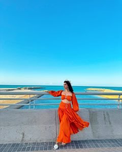 Ocean backdrop with Eshanya Maheshwari spinning in orange beach dress