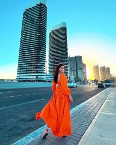 Eshanya Maheshwari playful beach pose in vibrant orange summer dress