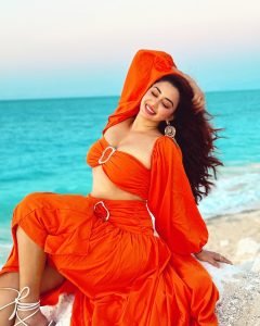 Eshanya Maheshwari playful beach pose in vibrant orange summer dress