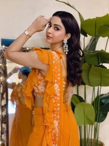 Eshanya Maheshwari relaxed pose in vibrant orange ruffle saree