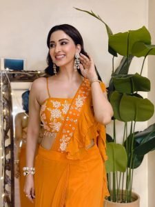 Eshanya Maheshwari relaxed pose in vibrant orange ruffle saree