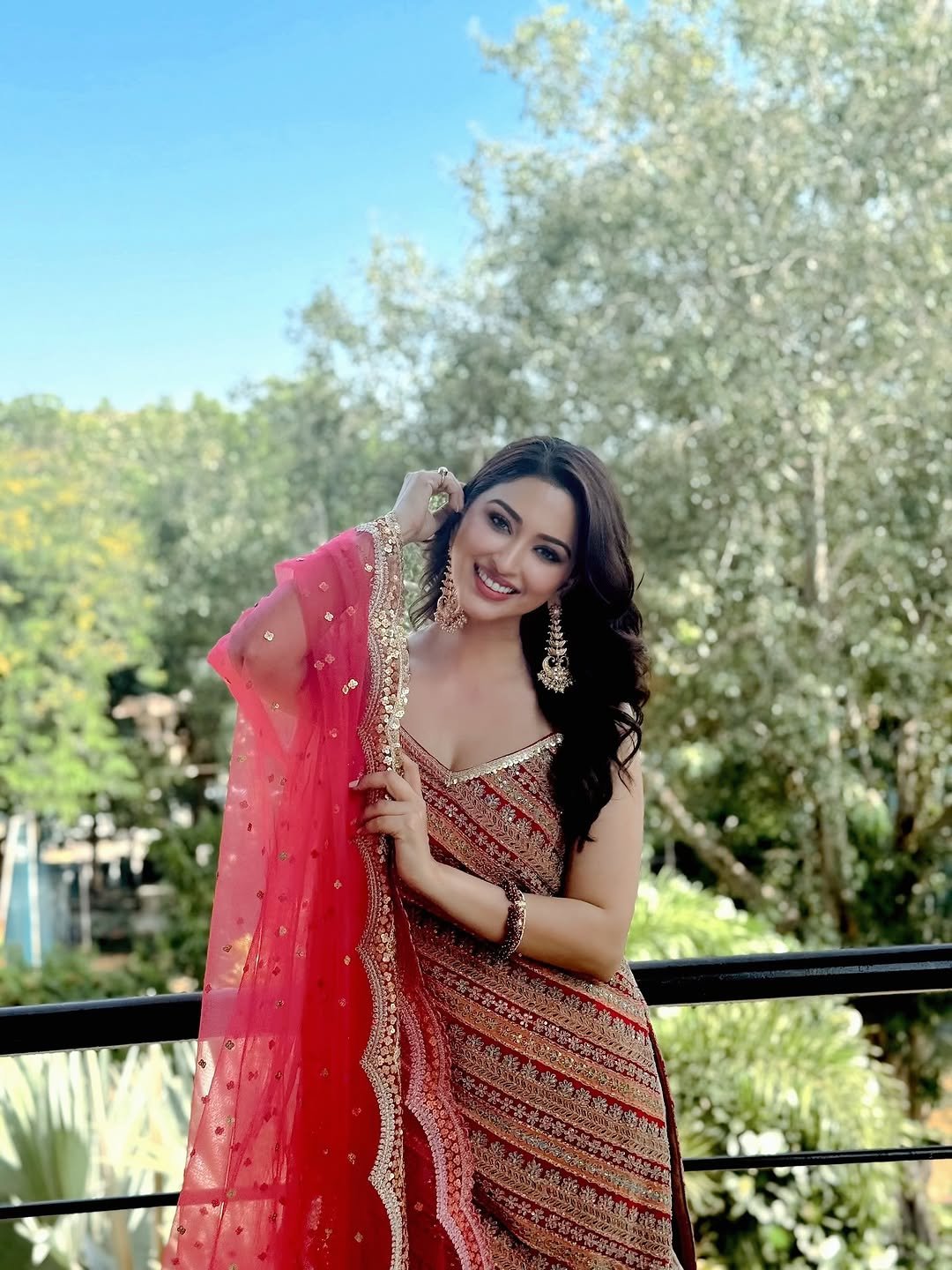 Daytime balcony shot of Eshanya Maheshwari in vibrant red lehenga