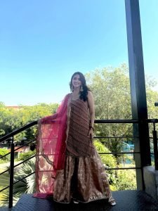 Daytime balcony shot of Eshanya Maheshwari in vibrant red lehenga