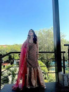 Daytime balcony shot of Eshanya Maheshwari in vibrant red lehenga