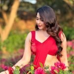 Eshanya Maheshwari in red saree standing amidst green garden foliage