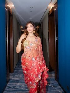 Malavika Mohanan elegant pose in coral saree artistic wall setting