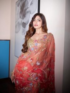 Malavika Mohanan elegant pose in coral saree artistic wall setting