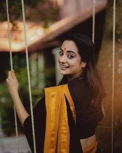 Namitha Pramod swinging in black saree with bright mustard border