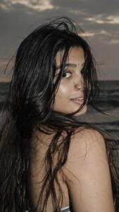 Ananthika walking barefoot near ocean in casual summer outfit