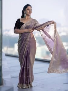 Anasuya sitting near brass lamp in handwoven saree with kolam on floor