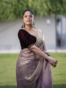 Anasuya sitting near brass lamp in handwoven saree with kolam on floor