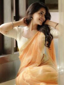 Dharshna sitting on verandah in peach saree with teacup in hand