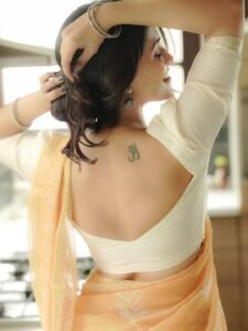 Dharshna sitting on verandah in peach saree with teacup in hand