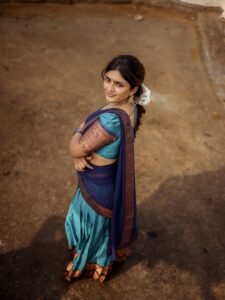 Eesha sitting by window in blue saree with antique mirror backdrop