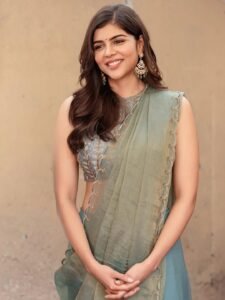 Kalyani sitting by window in green saree with antique mirror backdrop