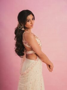 Preethi walking barefoot near ocean waves in minimalist white dress