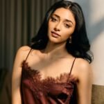 Close-up of Preethi with red lips and voluminous curls in maroon outfit