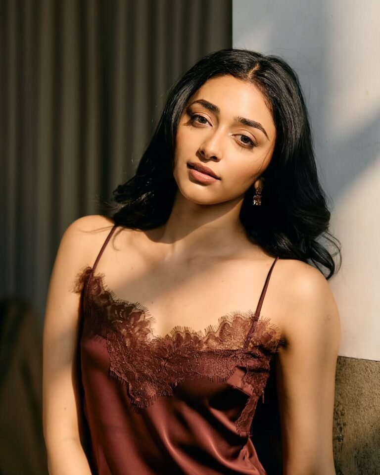 Close-up of Preethi with red lips and voluminous curls in maroon outfit