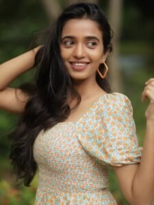 Close-up of Trupti with straw hat and loose waves in floral outfit